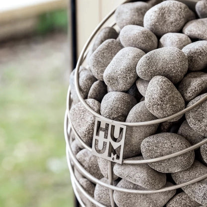 Close-up of HUUM Drop sauna stones in steel mesh frame